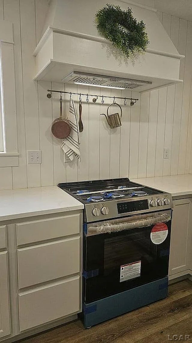 kitchen featuring white cabinets, stainless steel stove, dark hardwood / wood-style floors, and custom exhaust hood