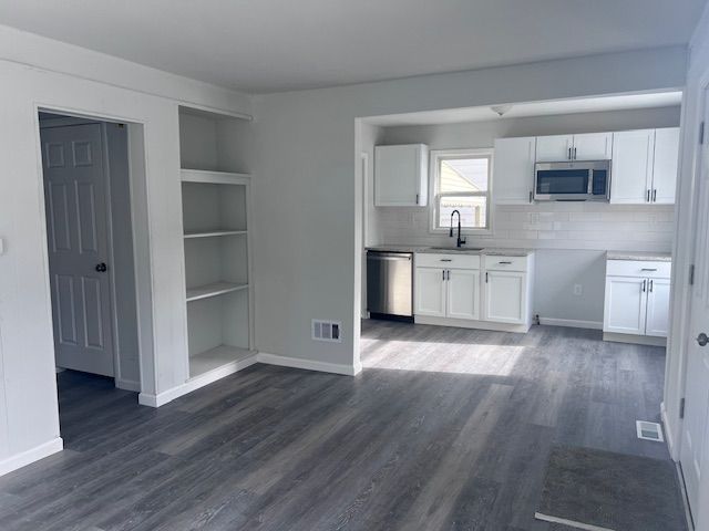 kitchen with sink, dark hardwood / wood-style flooring, decorative backsplash, white cabinets, and appliances with stainless steel finishes