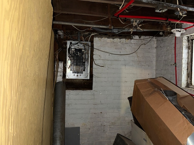 basement featuring electric panel and brick wall