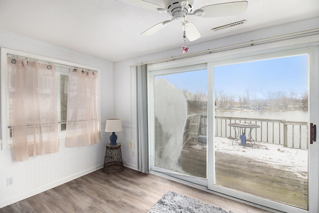 doorway featuring hardwood / wood-style floors, a water view, and ceiling fan