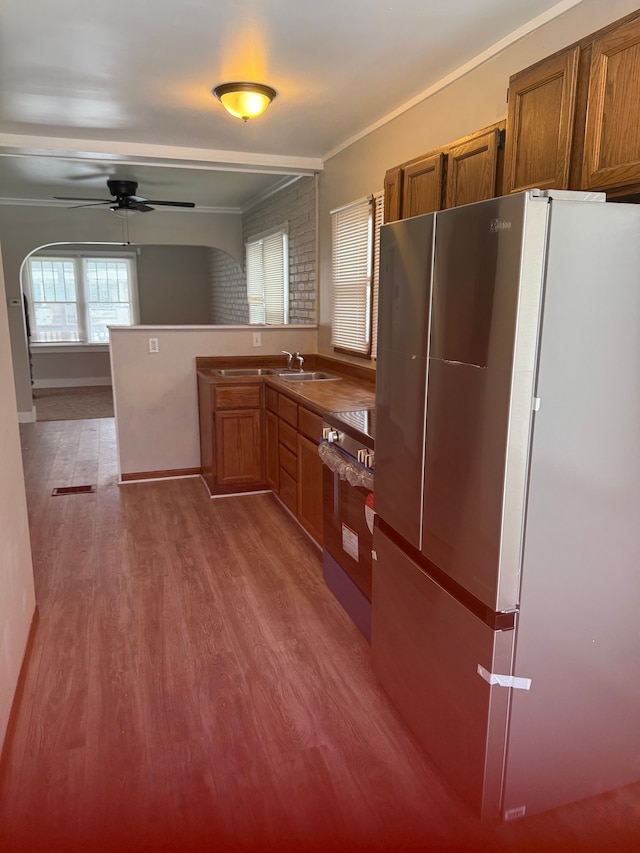 kitchen featuring ceiling fan, light wood-type flooring, stainless steel appliances, and ornamental molding