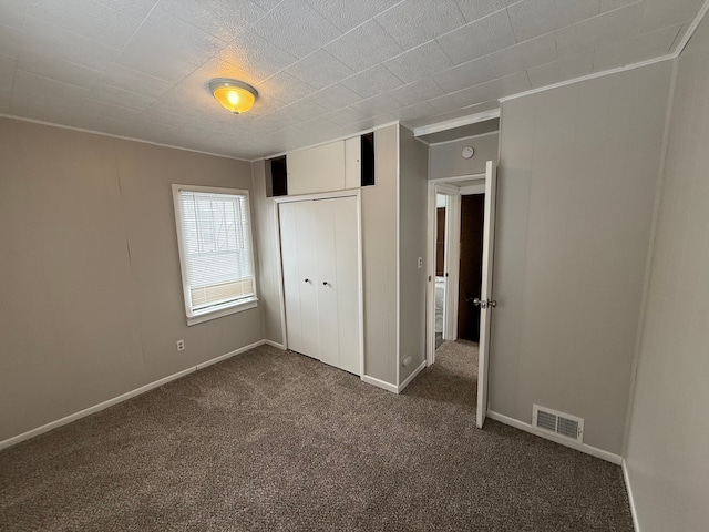 unfurnished bedroom with a closet and dark carpet