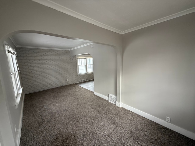 carpeted empty room with ornamental molding and brick wall