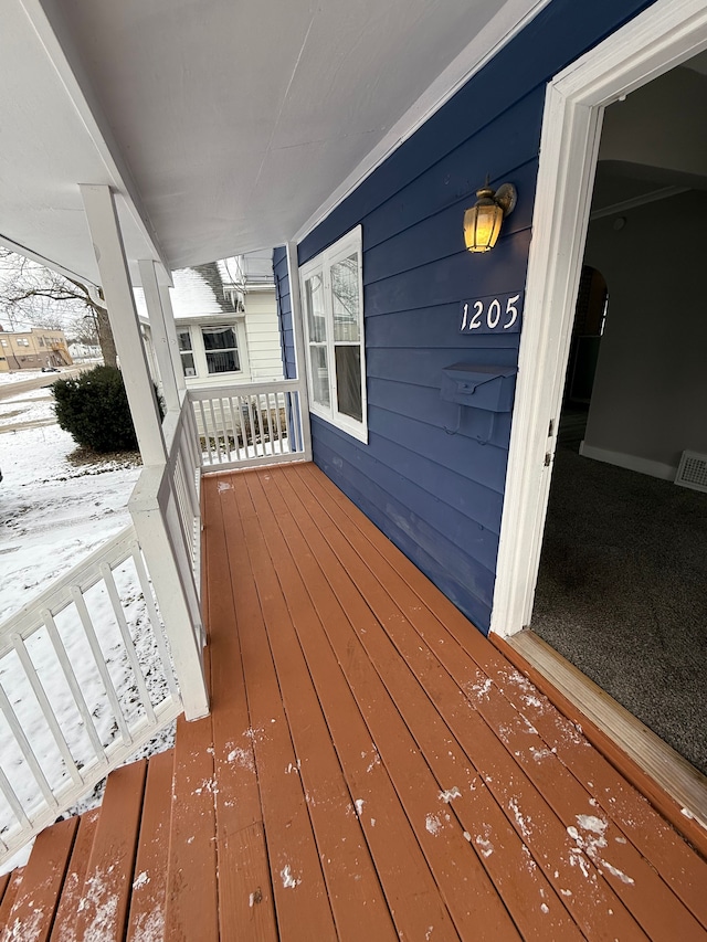 snow covered deck featuring a porch