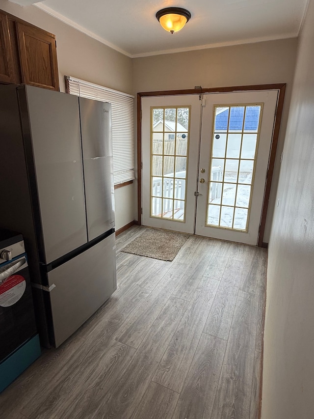 entryway with french doors, light wood-type flooring, and crown molding