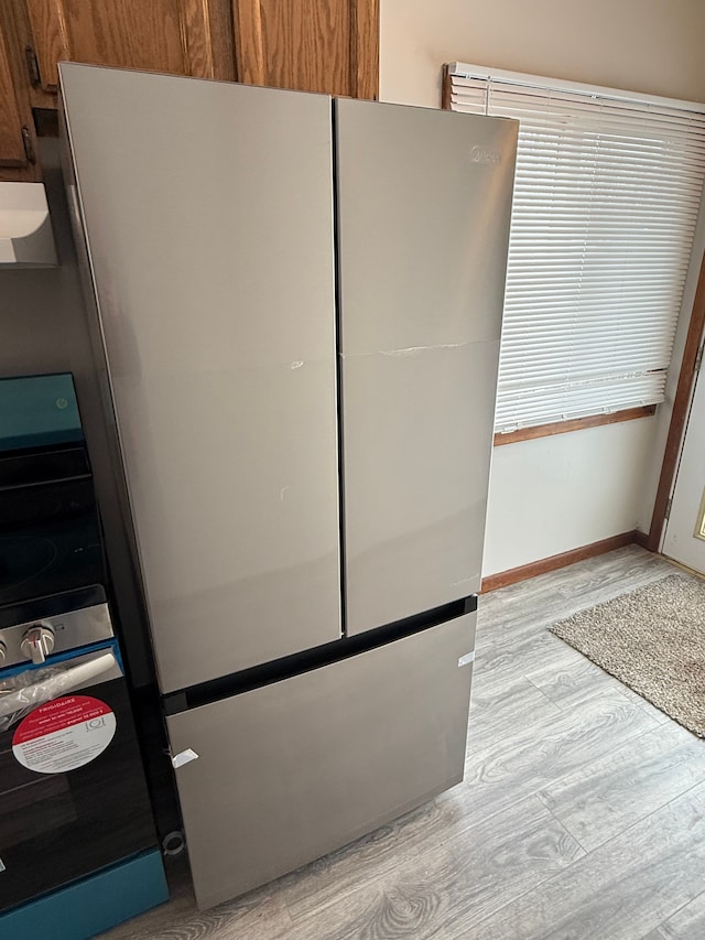 room details featuring stove, light hardwood / wood-style floors, and stainless steel refrigerator