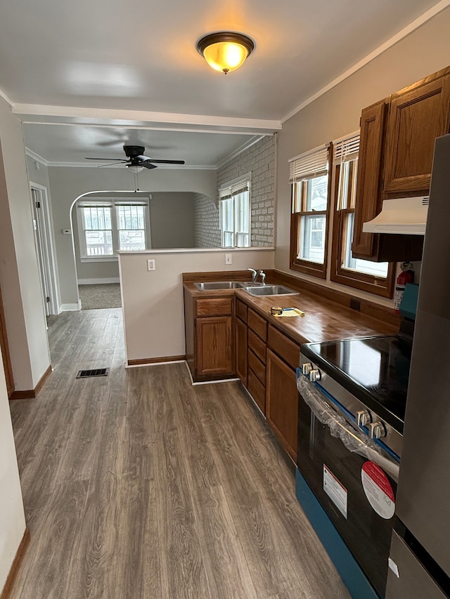 kitchen with stainless steel appliances, extractor fan, dark hardwood / wood-style floors, and ornamental molding