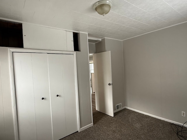 unfurnished bedroom featuring dark colored carpet and a closet