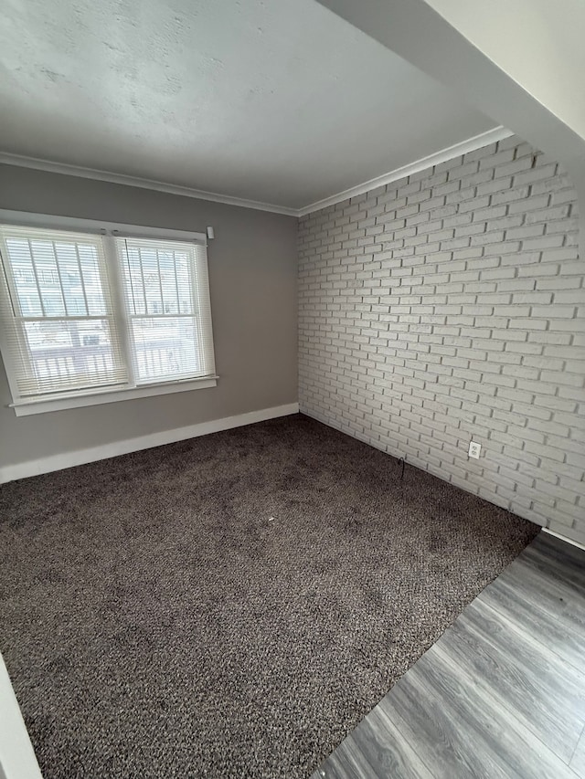 additional living space with hardwood / wood-style floors and brick wall