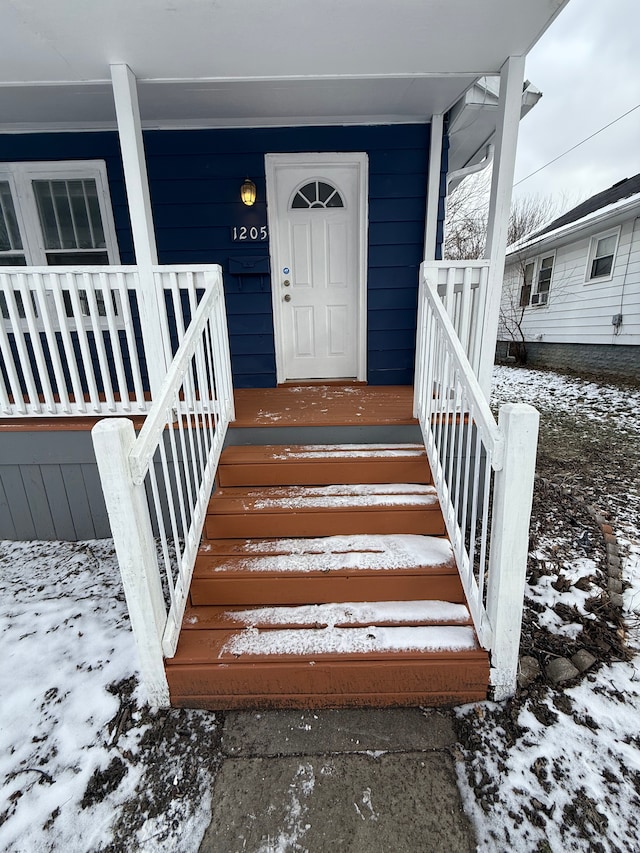 snow covered property entrance with covered porch