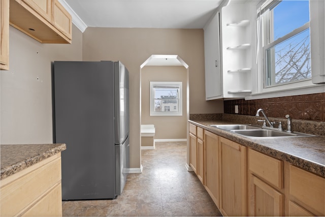 kitchen featuring sink, stainless steel refrigerator, light brown cabinetry, and decorative backsplash