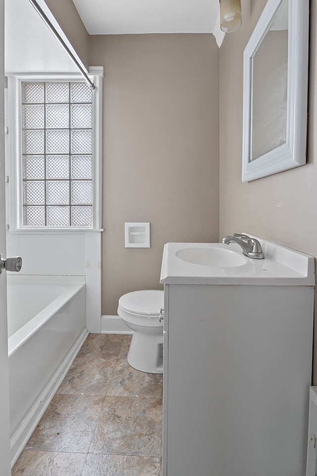 bathroom featuring toilet, a wealth of natural light, a bathtub, and vanity