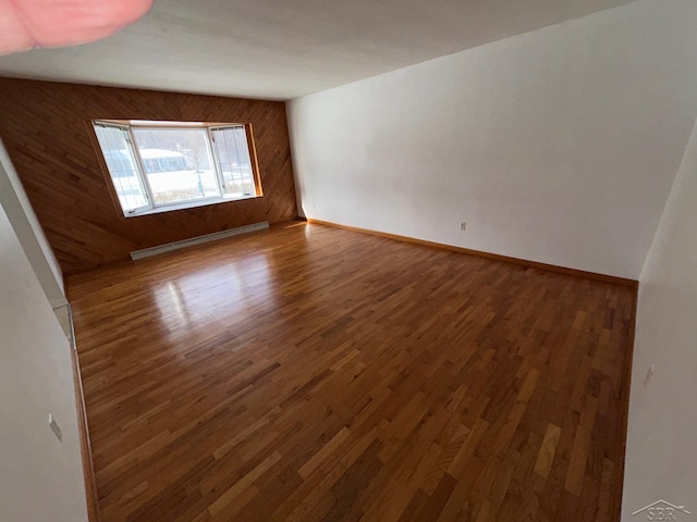 empty room with wood walls, a baseboard radiator, and dark hardwood / wood-style floors