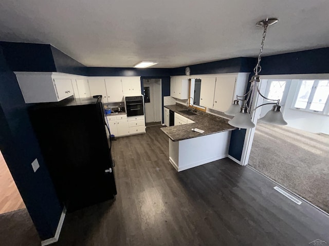 kitchen featuring kitchen peninsula, pendant lighting, white cabinetry, and black oven