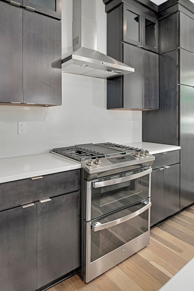 3634 Trumbull St Unit 65, Detroit, MI 48208 - kitchen featuring range with two ovens, wall chimney range hood, and light wood-type flooring