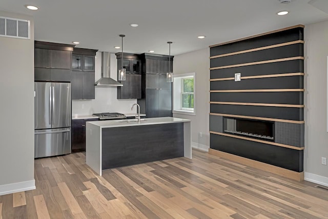 3634 Trumbull St Unit 65, Detroit, MI 48208 - kitchen featuring stainless steel fridge, sink, wall chimney range hood, decorative light fixtures, and a center island with sink