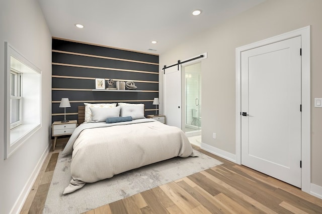 3634 Trumbull St Unit 65, Detroit, MI 48208 - bedroom featuring a barn door, light wood-type flooring, and connected bathroom