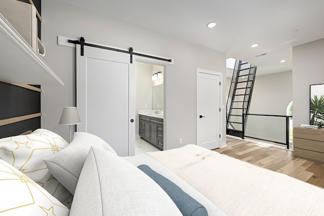 3634 Trumbull St Unit 65, Detroit, MI 48208 - bedroom with a barn door, light wood-type flooring, and connected bathroom