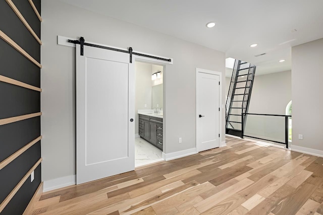 3634 Trumbull St Unit 65, Detroit, MI 48208 - unfurnished bedroom featuring ensuite bath, light wood-type flooring, and a barn door