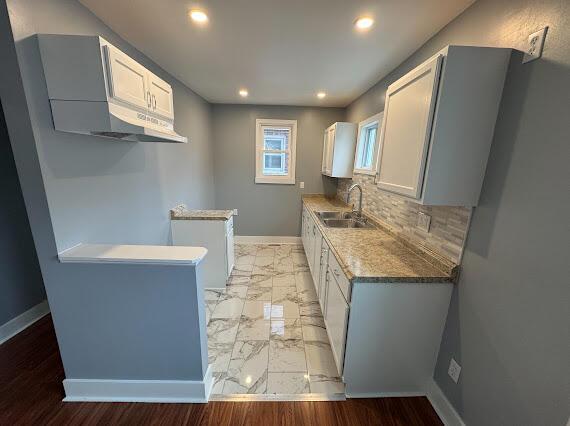 kitchen featuring white cabinets, sink, and tasteful backsplash