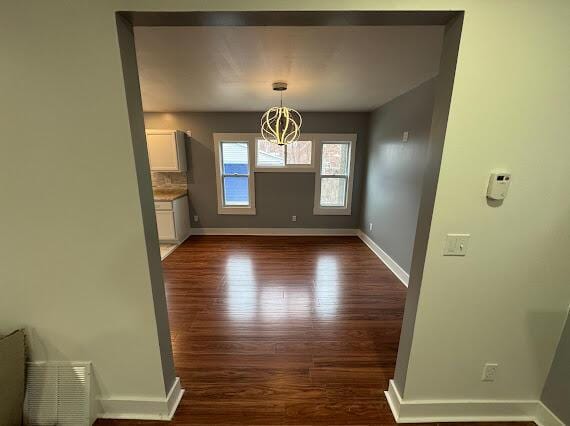 unfurnished dining area featuring dark hardwood / wood-style floors and a chandelier