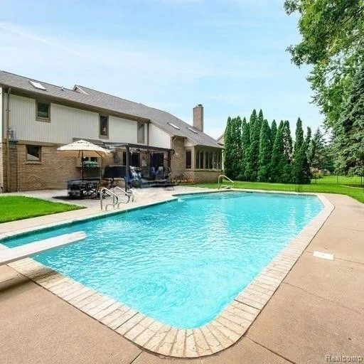 view of pool with a diving board and a patio