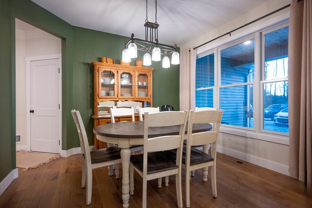 dining room with dark wood-type flooring and a notable chandelier