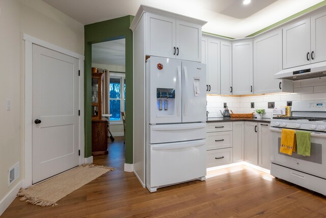 kitchen featuring white appliances, white cabinets, light hardwood / wood-style floors, and tasteful backsplash