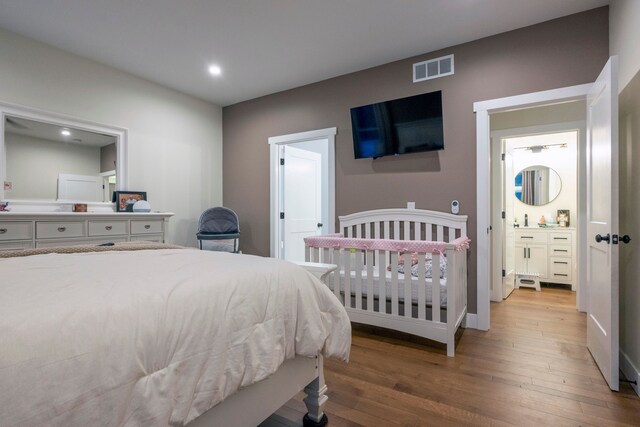 bedroom with ensuite bathroom and hardwood / wood-style flooring