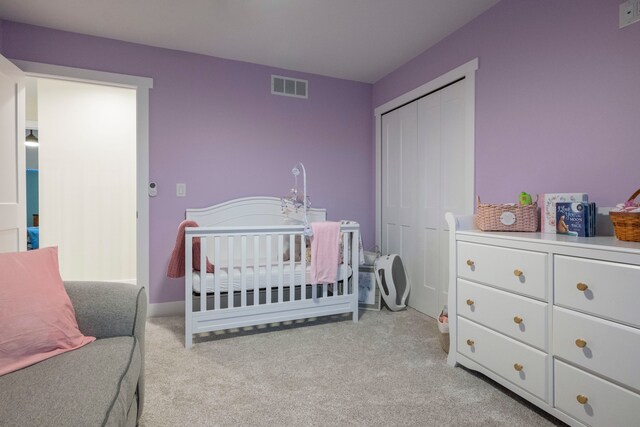 bedroom featuring light colored carpet, a closet, and a nursery area