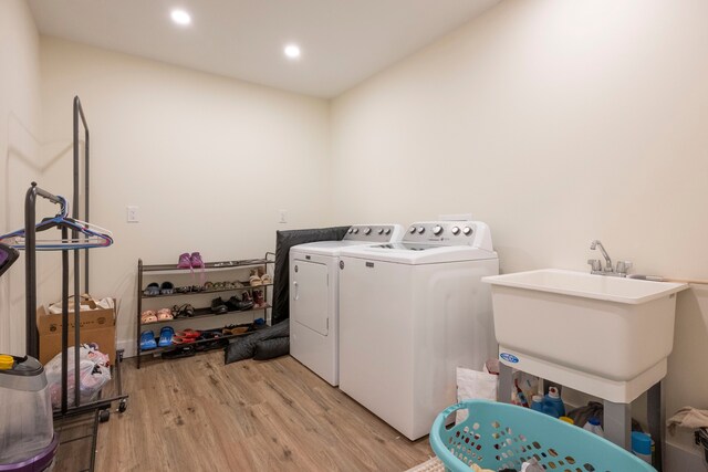 laundry room with washer and dryer, light hardwood / wood-style flooring, and sink