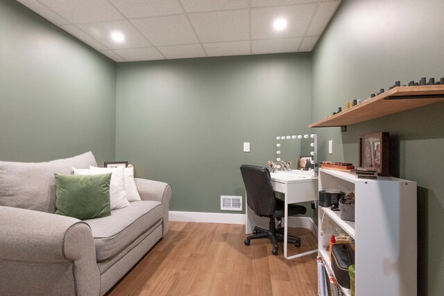 office with light hardwood / wood-style floors and a paneled ceiling