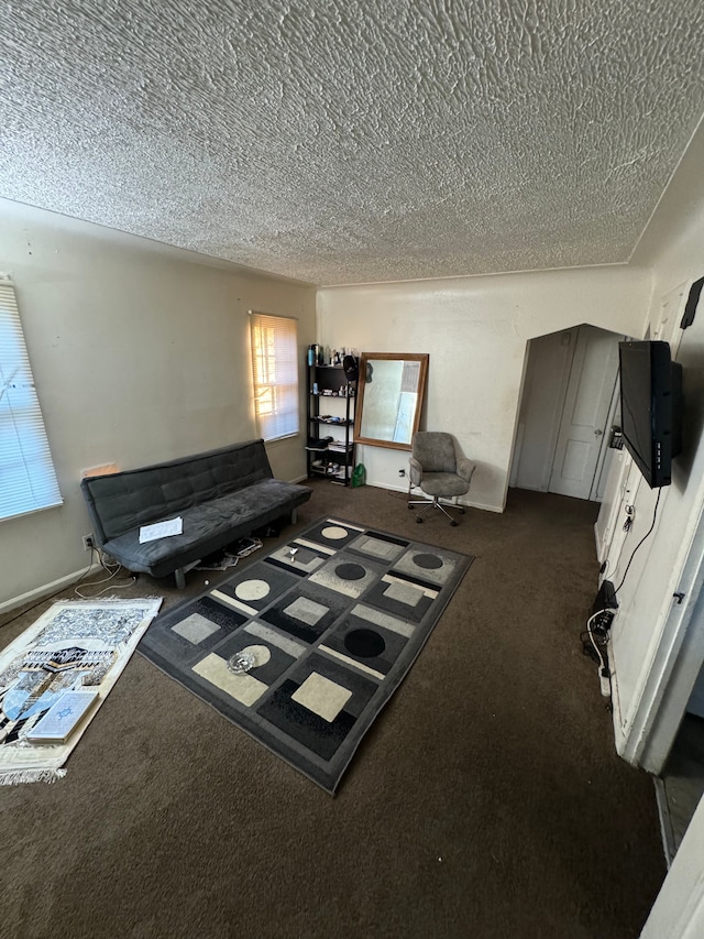 unfurnished living room featuring dark carpet and a textured ceiling