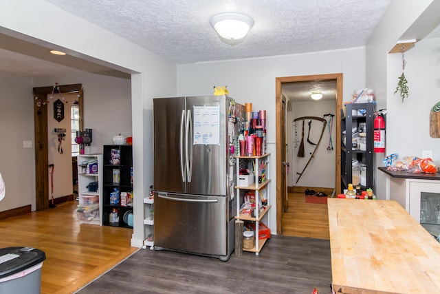 kitchen featuring a textured ceiling, stainless steel refrigerator, and dark wood-type flooring