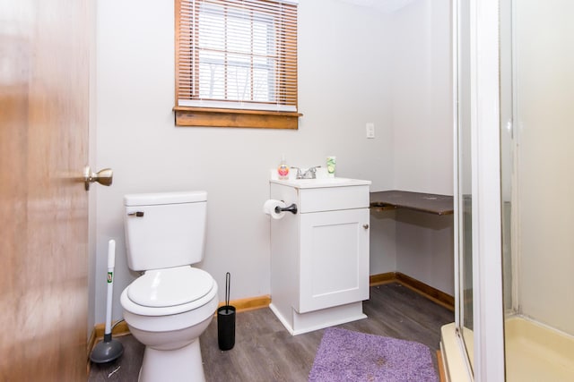 bathroom with hardwood / wood-style flooring, vanity, toilet, and walk in shower