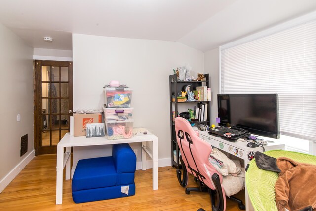 office space with vaulted ceiling and light hardwood / wood-style flooring