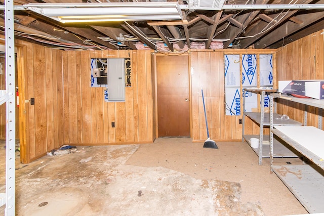 basement with electric panel and wood walls