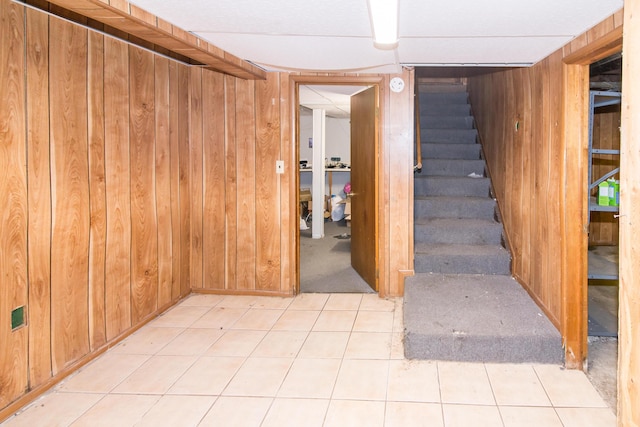 basement featuring light carpet and wood walls