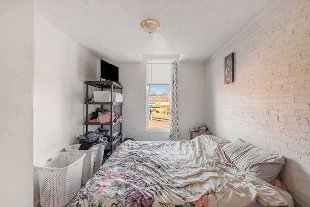 bedroom featuring brick wall and a textured ceiling