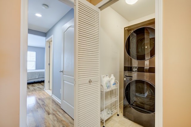 laundry area featuring light wood-type flooring and stacked washer / dryer