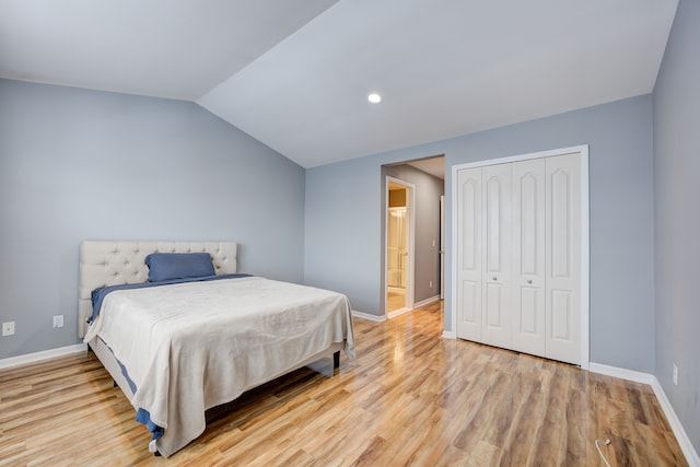 bedroom featuring light hardwood / wood-style floors, vaulted ceiling, and a closet