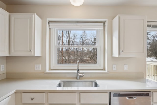 kitchen featuring stainless steel dishwasher, white cabinets, and sink