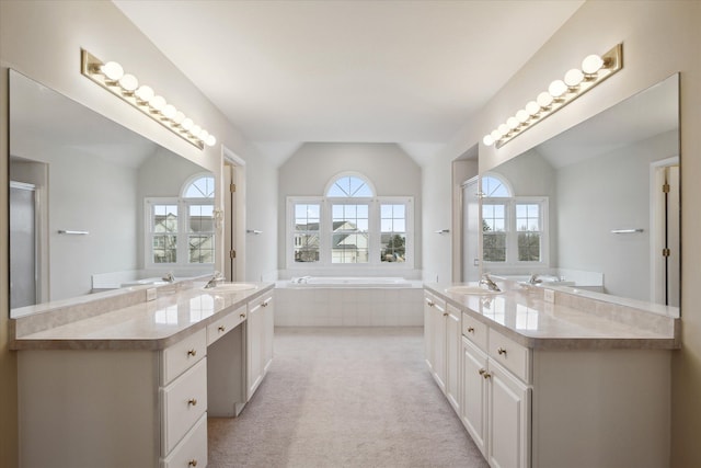 bathroom featuring a relaxing tiled tub, vanity, a wealth of natural light, and vaulted ceiling