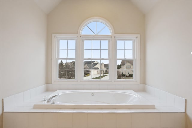 bathroom with tiled tub and lofted ceiling