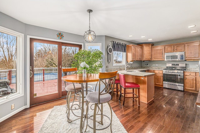 kitchen featuring dark wood-type flooring, a breakfast bar, sink, hanging light fixtures, and stainless steel appliances