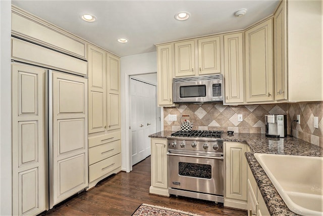 kitchen with dark wood-type flooring, cream cabinetry, appliances with stainless steel finishes, and sink