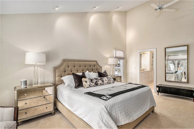 carpeted bedroom featuring ceiling fan, ensuite bathroom, multiple windows, and high vaulted ceiling