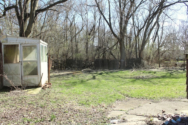 view of yard with fence, an outdoor structure, and a shed