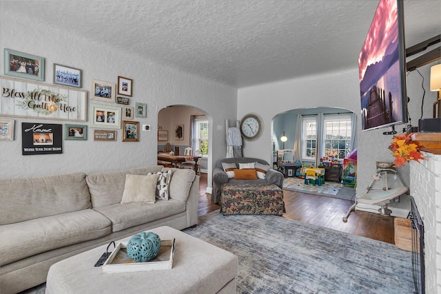 living room with a wealth of natural light, wood-type flooring, and a textured ceiling