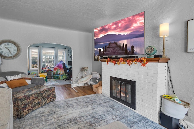 living room with hardwood / wood-style flooring, a fireplace, and a textured ceiling